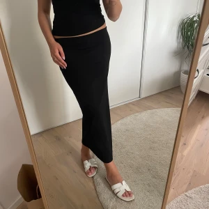 Svart midikjol - Svart midikjol med slit på baksidan. Bra skick, knappt använd.