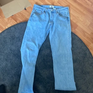 Levi's 501 jeans - Säljer ett par klassiska Levi's 501 jeans i ljusblå denim. De har en straight passform och är tillverkade i bomull. Jeansen har knappgylf och fem fickor. Perfekta för en avslappnad stil!