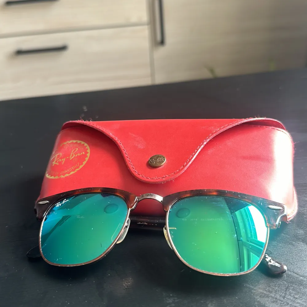 Säljer ett par snygga Ray-Ban solglasögon med gröna spegelglas och en klassisk brun sköldpaddsmönstrad båge. De kommer med ett rött fodral som har Ray-Ban-loggan i guld. Perfekta för soliga dagar och ger en cool look!. Accessoarer.