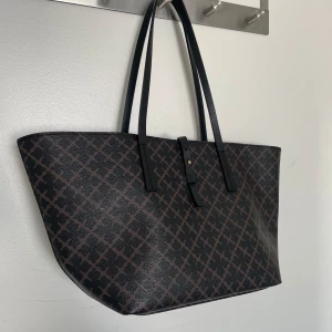 By Malene Birger handväska - Väskan är i nyskick på utsidan och insidan har en liten fläck men inga stora defekter utöver det. Den är sparsamt använd några gånger. Den är 41 x 21 cm.