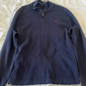 Säljer en snygg mörkblå halfzip från Polo Ralph Lauren i storlek XL. Tröjan har en halv dragkedja och det klassiska röda Polo-loggan broderad på bröstet. Perfekt för höst och vinter med sin stilrena design och bekväma passform. Passar både till vardags och lite finare tillfällen.