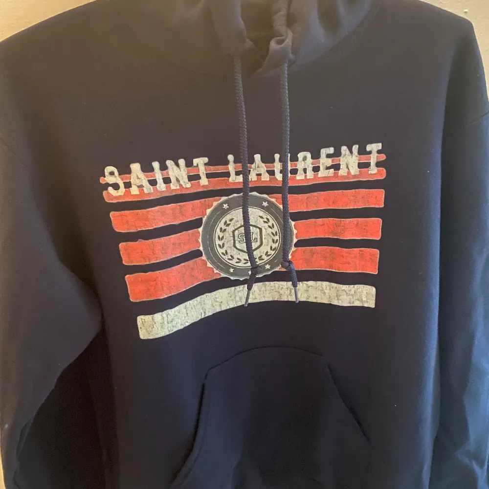 Säljer en Hoodie som ska efterlikna en Saint Laurent Hoodie. tröjan är i färgen Marinblå och i storleken S. Skicket är 10/10.. Hoodies.