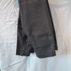 Svarta byxor från Zara Woman - Säljer ett par khaki byxor från Zara Woman Premium Denim Collection. Byxorna har en snygg dragkedja vid bensluten och är gjorda i ett slitstarkt material. Perfekta för både vardag och fest!