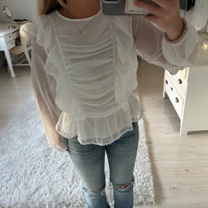 Vit blus med volanger - En vit volangblus från Lindex. Strl 164 men passar på xs-m då den är elastisk i midjan. Endast använd ett fåtal gånger. Pris kan diskuteras🤍