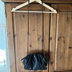 Svart axelremsväska i konstskinn - Säljer en svart söt axelremsväska i konstskinn med magnetiskt stängningsfunktion 💕💕 sällan använd 