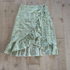 Grön blommig kjol - Grön kjol med vita blommor, mellanlång med dragkedja och knyta