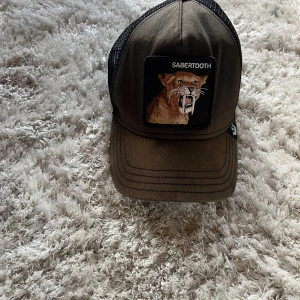 Brun keps med sabeltandad tiger från Goorin Bros - Säljer nu en tvär fin keps. Kepsen har inte används så mycket men har stått ute i solen så har blivit lite brun🔥priset gå att förhandlas 🤩Skriv om fler frågor eller bilder🔥🔥