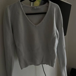 Vit tröja från Zara - Säljer en superfin vit tröja från Zara. Den är i storlek S och har en snygg v-ringning. Tröjan är långärmad och perfekt för både höst och vinter. Materialet känns mjukt och mysigt, perfekt för kyliga dagar!