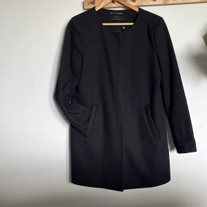 Svart kappa från ONLY - Säljer en stilren svart kappa från ONLY i storlek M. Den har en enkel design med långa ärmar och en diskret knäppning framtill. Perfekt för både höst och vår, och funkar lika bra till vardags som till fest. Materialet känns mjukt och bekvämt att ha på sig.