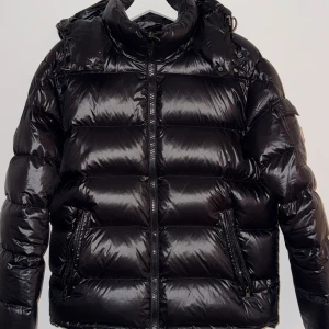 Svart pufferjacka  - Säljer en snygg svart pufferjacka. Jackan har en glansig finish och är utrustad med dragkedja framtill. Den har långa ärmar och en hög krage för extra värme. Perfekt för kyliga dagar!