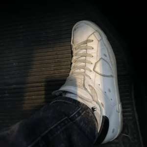 Vita sneakers från Phillipe model - Snygga vita sneakers med klassisk snörning och en stilren design. Perfekta för en avslappnad stil. Skorna har en vit sula och är väldigt stilrena. Enda lilla defekten är att det är lite upprivet på undersidan av skon men det är endast på hälen på ena skon