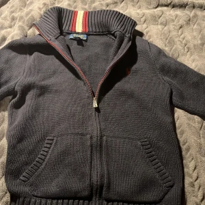 Stickad Ralph Lauren Zip 10-12y passar till 156cm - 9/10 skick väldigt snygg Ralph lauren stickad zip som passar till klädstilen grisch och stockholm stil. Tröjan är size 10-12y men passar lite äldre och lite yngre beroende av längd och vikt. Ställ gärna frågor! Svarar snabbt!