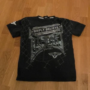 Svart T-shirt från Tapout - Cool svart T-shirt från Tapout med snygg camo färgad text på framsidan, passar för personer som gillar att klä sig svart eller som bara vill ha lite y2k stil 🔥🖤 *PRISET KAN DISKUTERAS* 