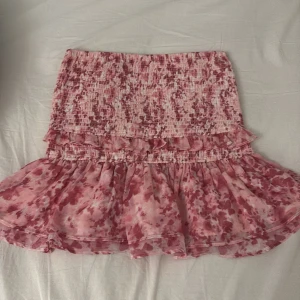 Rosa volangkjol från Gina Tricot - Söt rosa kjol från Gina Tricot med volanger och ett härligt mönster. Kjolen är kort och har en elastisk midja för bekväm passform. Den är skulle kunna passa M med💕Den är köpt från Plick tidigare med avklippta lappar skulle kunna säga att den passar S och M💕