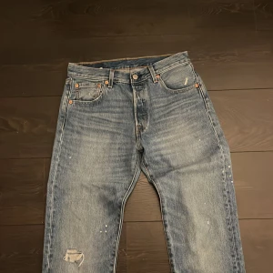 Levis 501 jeans - Säljer dessa riktigt feta levis 501or. De har en skön tvätt och ett hål i knät, dock ser hålet bra ut och är gjort med mening. Pris kan gå ner vid snabb affär och frakt sker samma dag om köpet är innan 20:00. Jeansen har vit färg på sig, men det är inget som syns från långt håll och dessutom kan det matchas med t.ex paint splatter margielas eller helmut lang paint splatter hoodie.