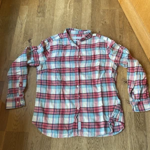 Rutig skjorta från Peak Performance - Säljer en snygg rutig skjorta från Peak Performance i storlek XL. Skjortan har en klassisk krage och knappar framtill. Färgerna är en mix av rött, blått och vitt, vilket ger en fräsch look. Perfekt för en avslappnad stil. 100%Bomull