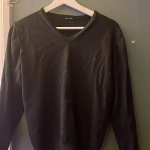 Svart merinoulltröja från Sand - Snygg grå tröja från Sand i extra fin merinoull. Tröjan har en v-ringad design och långa ärmar, perfekt för kyligare dagar. Den är stilren och passar bra till både vardag och mer uppklädda tillfällen.