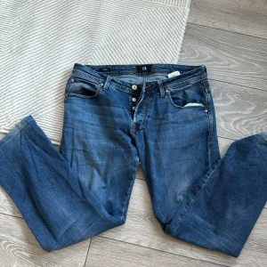 Blå jeans från LTB - Snygga blå jeans från LTB med klassisk femficksdesign och knappgylf. De har en stilren look med subtila slitningar och broderade bakfickor. Perfekta för en avslappnad stil.