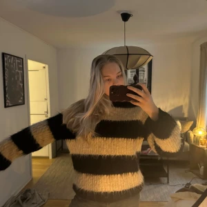 Randig stickad tröja - Säljer en mysig stickad tröja med breda ränder i svart och beige. Köpt på arket och gjord på alpacka och ull.