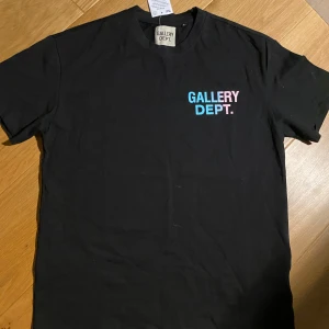 Svart t-shirt  - Snygg svart t-shirt . med färgglad text i rosa och blått på bröstet och ryggen. Perfekt för en avslappnad stil.