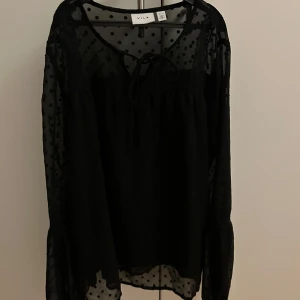 Svart prickig blus från Vila - Säljer en svart blus från Vila med prickigt mönster och spetsdetaljer. Blusen har långa ärmar och en knytning framtill. Använd fåtal gånger och bra skick. 🤗