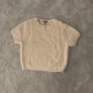Beige fluffig tröja från H&M - Mysig beige tröja från H&M i fluffigt material. Perfekt för en avslappnad och bekväm stil. Tröjan har korta ärmar och en rund halsringning.