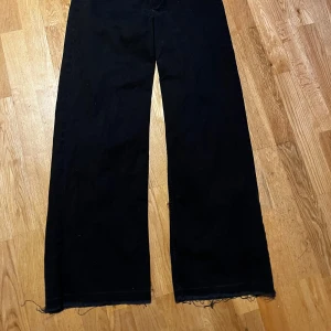 Svarta vida jeans  - Snygga svarta byxor med en vid passform och hög midja. Perfekta för en stilren look. Byxorna har en klassisk design med knappar och dragkedja framtill.  (Ligger ute på andra sidor)