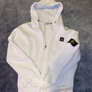 Vit huvtröja med dragkedja från Stone Island - Säljer en vit zip hoodie från Stone Island i använt skick, storlek L. Säljes då den är för stor för mig. Kan hämtas i Skövde men kan också fraktas! Mvh Lukas.
