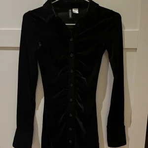 Skimrande sammetsklänning - Långärmad klänning i mjukt sammetstyg. Klänningen har knappar framtill och är figursydd!