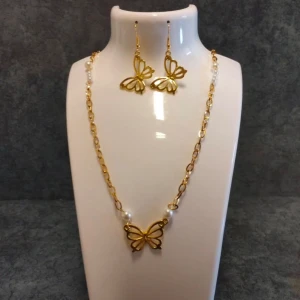 Guldhalsband och örhängen med fjärilar - Elegant set med halsband och örhängen i guld med fjärilsmotiv. Halsbandet har en tunn kedja med små pärlor och en fjäril som hänge. Örhängena matchar med samma fjärilsdesign. Perfekt för att lägga till en touch av elegans.