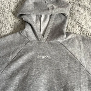 Grå hoodie från Gina Tricot - Säljer en stilren grå hoodie från Gina Tricot med texten 'do good.' på bröstet. Perfekt för en avslappnad look. Hoodien har en klassisk design med huva och mjukt material.