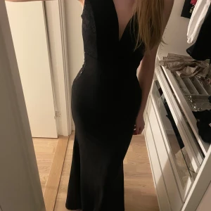 Långklänning - Svart långklänning med v-ringning och spetsdetaljer på sidorna och överdelen. Bara använd en gång