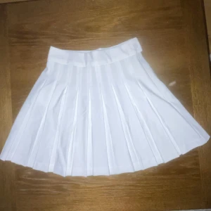 Vit plisserad kjol - Snygg vit plisserad kjol med en klassisk design. Perfekt för en stilren look. Kjolen har en normal passform och är gjord i ett lätt och bekvämt material.