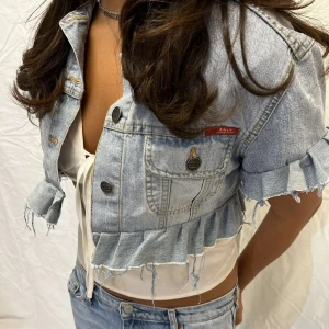 Blå croppad jeansjacka från DH-LY - Säljer en cool croppad jeansjacka i ljusblå denim. Jackan har aldrig används och säljer då den inte kommer till användning. Skriv för mer info!