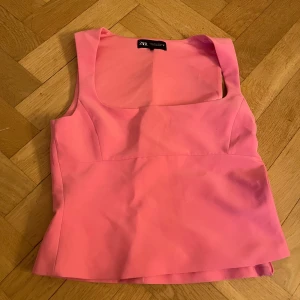 Rosa ärmlös topp från Zara - Snygg rosa ärmlös topp från Zara med en dragkedja på sidan. Perfekt för en stilren look. Toppen har en fyrkantig urringning och är i ett mjukt material.
