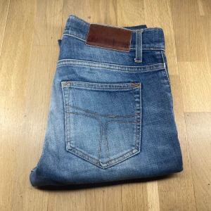 Tiger of sweden jeans - Snygga tiger of sweden blå jeans med en klassisk femficksdesign och ljusa tvättade detaljer. De har en knapp och dragkedja framtill samt en läderpatch på baksidan av midjan.