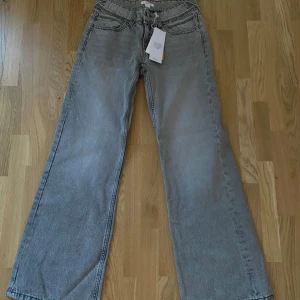 Grå jeansbyxor med vida ben - Snygga grå jeansbyxor från H&M med vida ben och hög midja. Byxorna har en klassisk femficksdesign och stängs med dragkedja och knapp. Perfekta för en avslappnad stil och kan stylas med allt. Midjemått är ca 35-36 cm rakt över, innerbenslängd är ca 77cm. Helt nya bara provad. Passar mig bra i längden som är 160. Nypris 349kr
