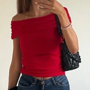 Röd offshoulder topp från Stradivarius - Har en åtsittande passform med rynkade detaljer. Endast använd en gång så i nyskick. Strl XS