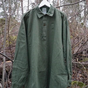 Svensk militär skjorta M7320 - 🪖Säljer en grön långärmad militär skjorta🪖 Skjortan har en klassisk krage och knappar framtill. Perfekt för en vintage-look🌟❌två små hål på den vänstra sidan av bröstet❌Ingen storlekslapp men passar som S-M