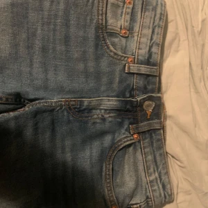 Blå jeans med bootcut - Snygga blå, lågmidjade bootcut jeans med en gul söm. Används ett fåtal gånger så det inte finns några slitningar på det. Innebenslängd: 75cm, midja rakt över: 35 cm