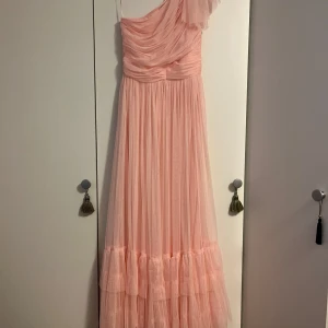 Ljusrosa långklänning med volang - Elegant ljusrosa långklänning med oneshoulder-design och volangdetaljer. 