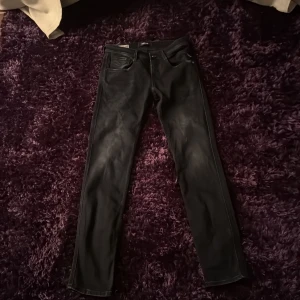 Svarta jeans från Replay 27/30 - Snygga svarta jeans från Replay med en klassisk femficksdesign. De har en rak passform och är perfekta för en stilren look. Jeansen har en dragkedja och knapp framtill.
