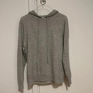Ljusgrå Kashmirhoodie - Säljer en stilren grå hoodie från Studios i storlek S. Tröjan har en klassisk design med huva och dragsko, perfekt för en avslappnad look. Den är tillverkad i ett mjukt material som ger en skön känsla. Perfekt för kyligare dagar!