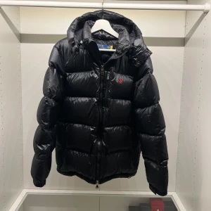 Svart pufferjacka från Polo Ralph Lauren - Snygg svart pufferjacka från Polo Ralph Lauren. Skick 10/10 om man inte räknar med defekten på sista bilden, kvitto finns, köpt på Raffes hemsidan för 5500kr. Vid minsta fundering hör av er 
