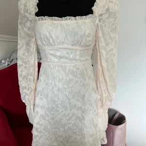 Miniklänning helt NY och oanvänd - Mycket smickrande figurnära miniklänning med långa skira ärmar. Helt NY och oanvänd. 