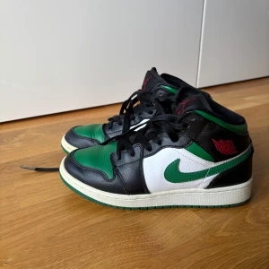 Nike Air Jordans i grönt, svart och vitt - Säljer ett par snygga Nike Air Jordans i grönt, svart och vitt. De har en cool design med klassisk snörning och den ikoniska Nike-loggan på sidan. Perfekta för både vardag och fest!