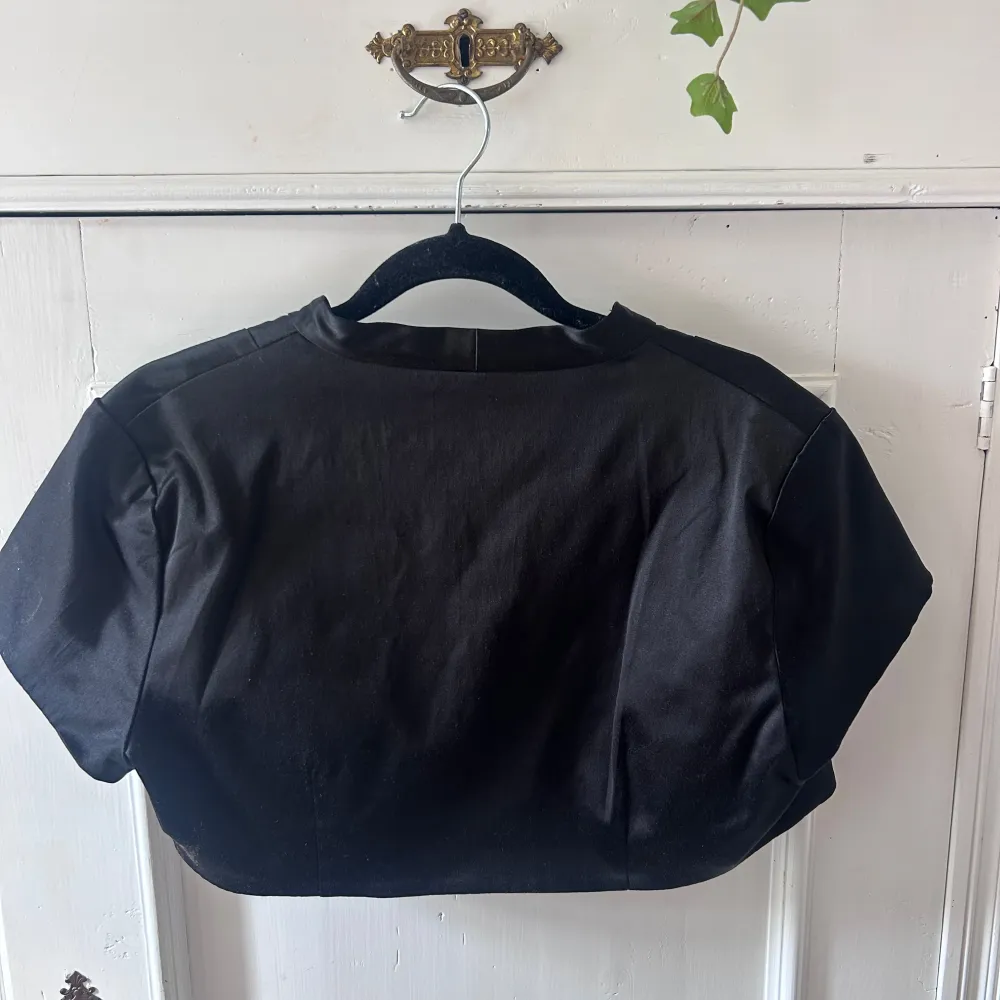 Säljer en elegant svart bolero från Be Beau. Den är kortärmad och har en stilren design som passar perfekt till festliga tillfällen. Materialet känns mjukt och lyxigt, vilket gör den både bekväm och snygg. Perfekt att ha över en klänning . Jackor.