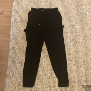 Svarta mjukisbyxor med snörning - Säljer ett par svarta mjukisbyxor i skönt material. De har en elastisk midja med snörning för bästa passform. Perfekta för en chill dag hemma eller en snabb tur till affären. 🖤