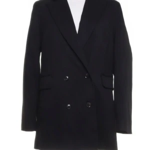 Svart kappa från BikBok - Säljer en stilren svart kappa från BikBok i storlek S. Den har en klassisk design med dubbelknäppning och långa ärmar. Materialet är en blandning av polyester, viskos och elastan, vilket gör den både bekväm och hållbar. Perfekt för höst och vinter!