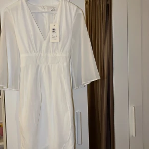 Klänning - Vit klänning i storlek 34. Helt ny och helt oanvänd sedan inköp!! Kanske din nästa studentklänning?😉